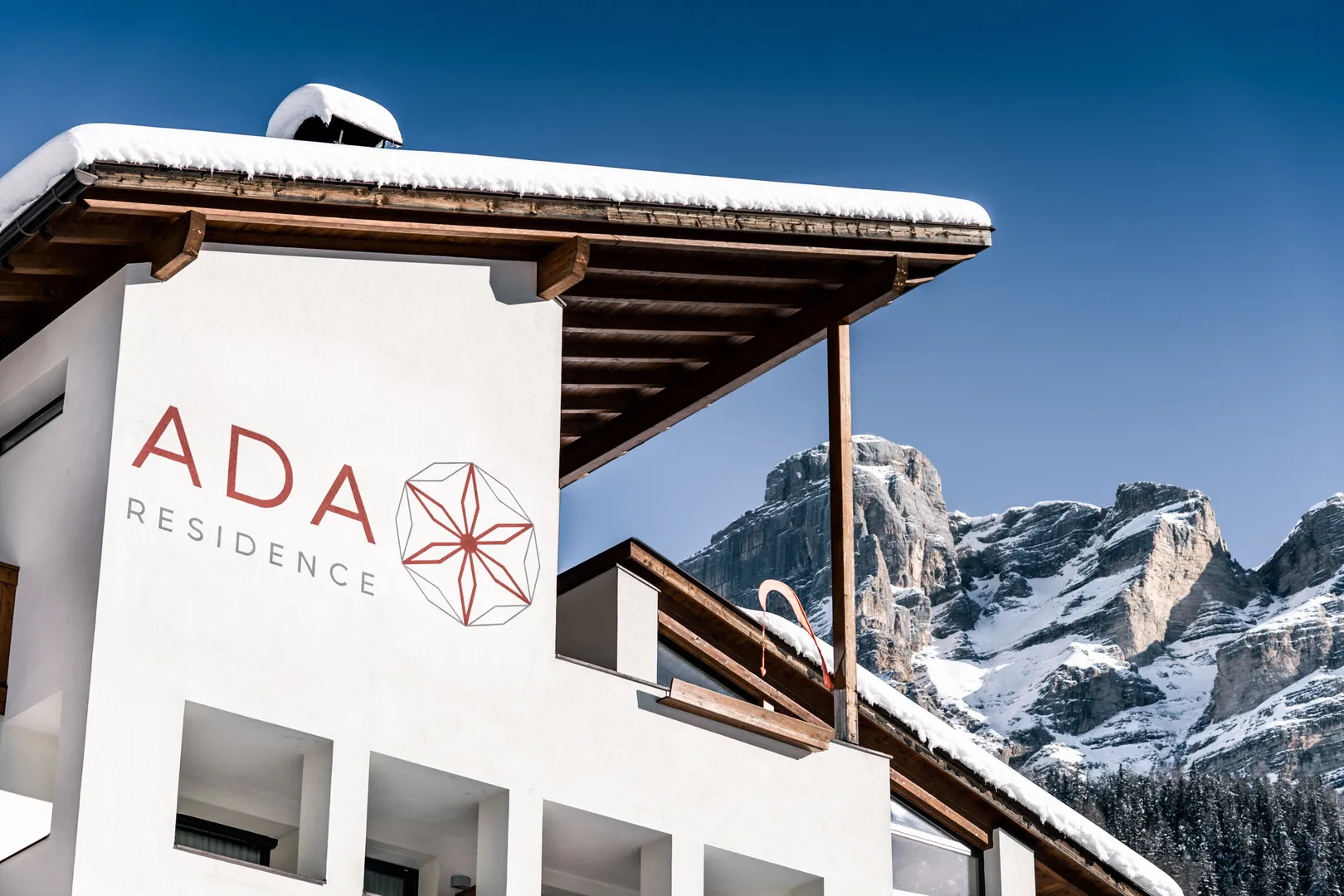 Residence Ada - insegna sulla facciata con le Dolomiti innevate